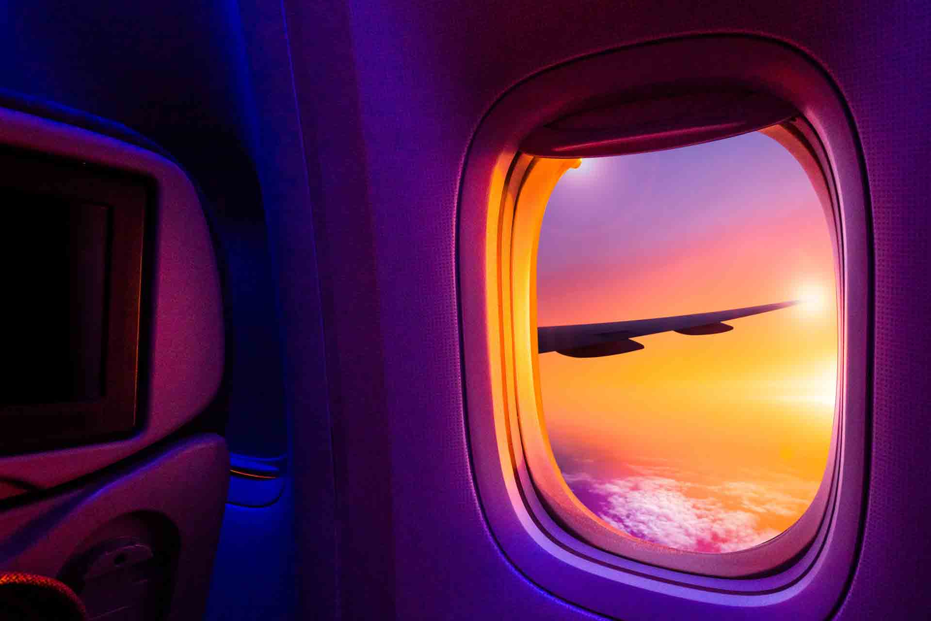 Blick aus einem Flugzeug bei Sonnenuntergang in Violett-orangem Licht